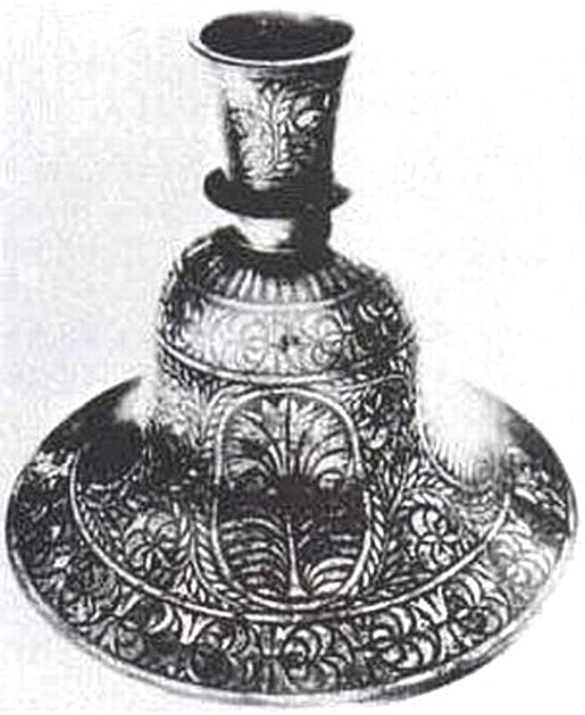 Взрыв вынес на поверхность две половинки предмета, названного «колоколом». Его высота составляет 12 см, толщина стенок из металлического сплава – 0,3 см. На поверхности  (диаметр «колокола» 16,5 см) серебром выложены аппликации в виде веночка и шести цветков. Ни эта находка, ни подобные ей не находят объяснения до сих пор относительно назначения, происхождения и производства.